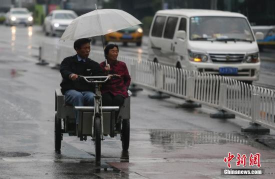 資料圖：民眾在雨中出行。<a target=