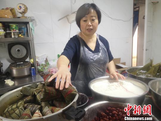 鄭春玲將兩張大粽葉窩成漏斗狀，填上糯米，放上兩粒紅棗，再加一片小粽葉，用棉線纏繞綁好，一個紅棗粽就成了，用時僅8秒?！「呖档?攝